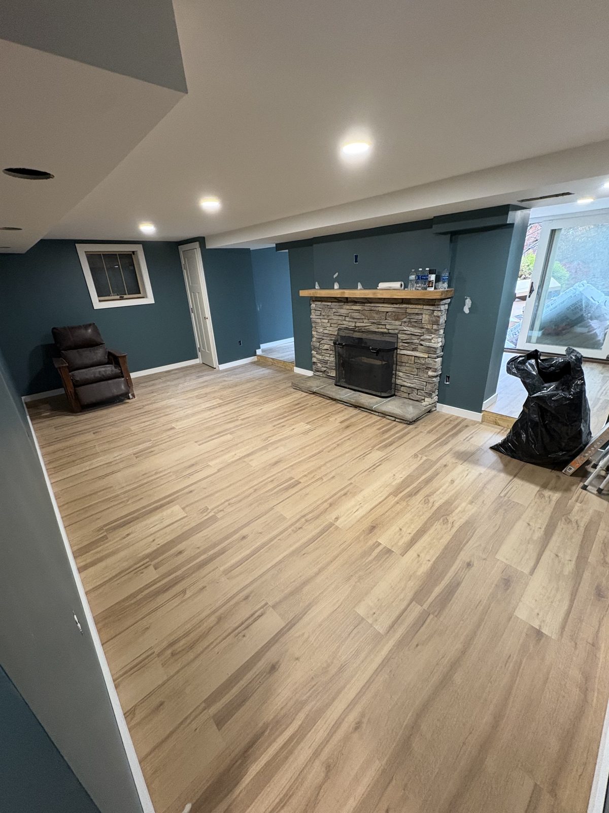 Finished basement with a stacked-stone fireplace and wide-plank floor
