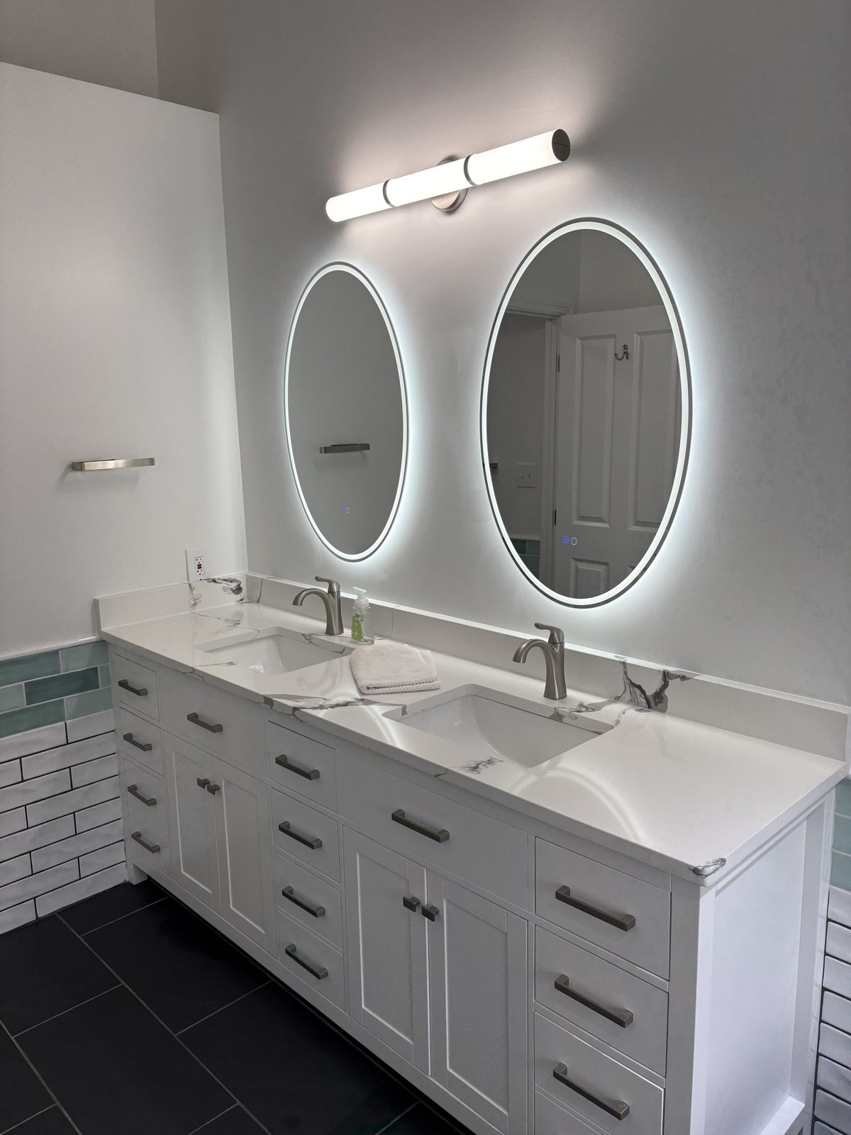 Double vanity under two backlit oval mirrors