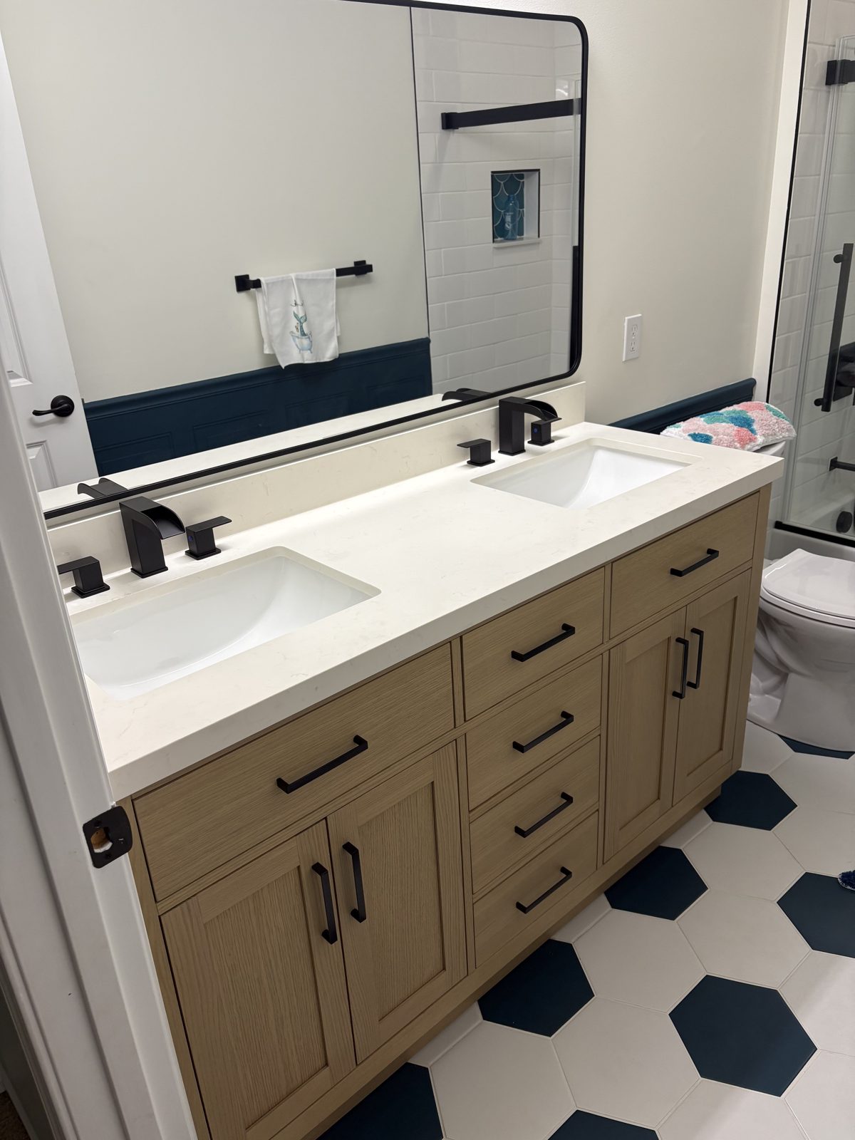 Natural wood double vanity with black hardware on hexagon tile