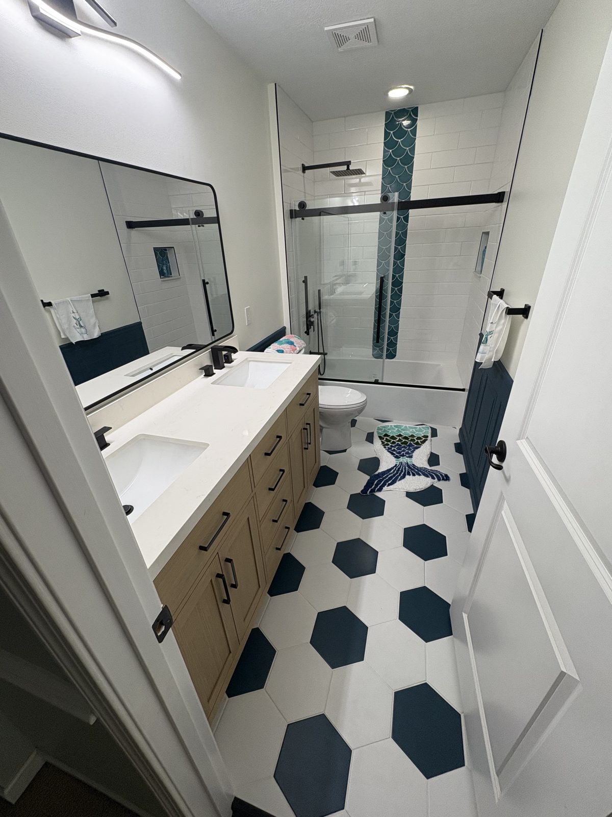 Bathroom with black and white hexagon floor tile and a wood vanity