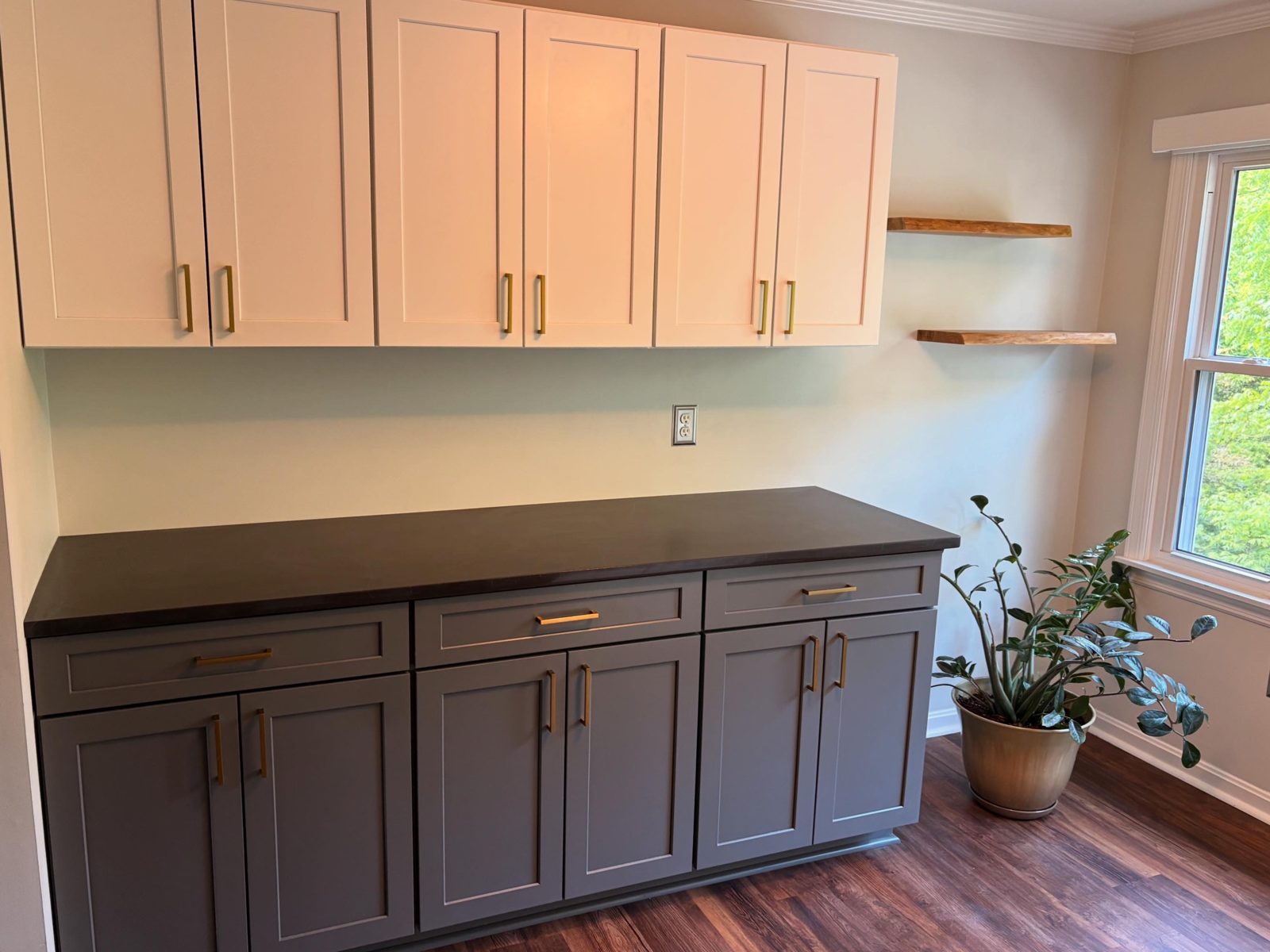 Gray base cabinets with a black countertop, white uppers and floating wood shelves