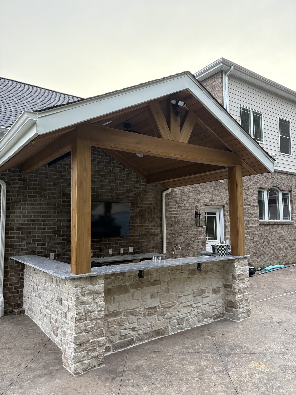 Covered patio with cedar beams and a stone-faced outdoor kitchen
