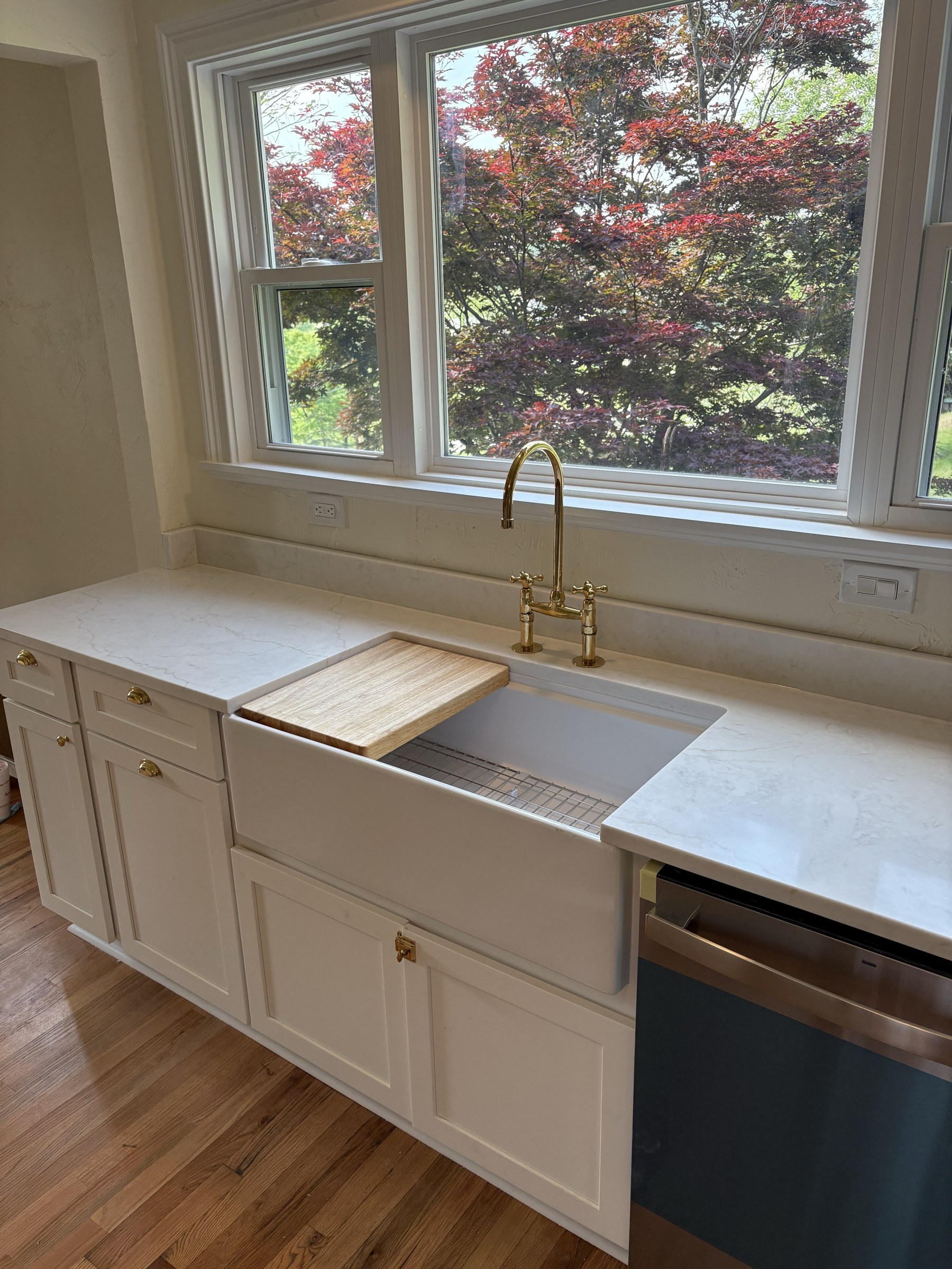 Apron-front farmhouse sink with brass bridge faucet