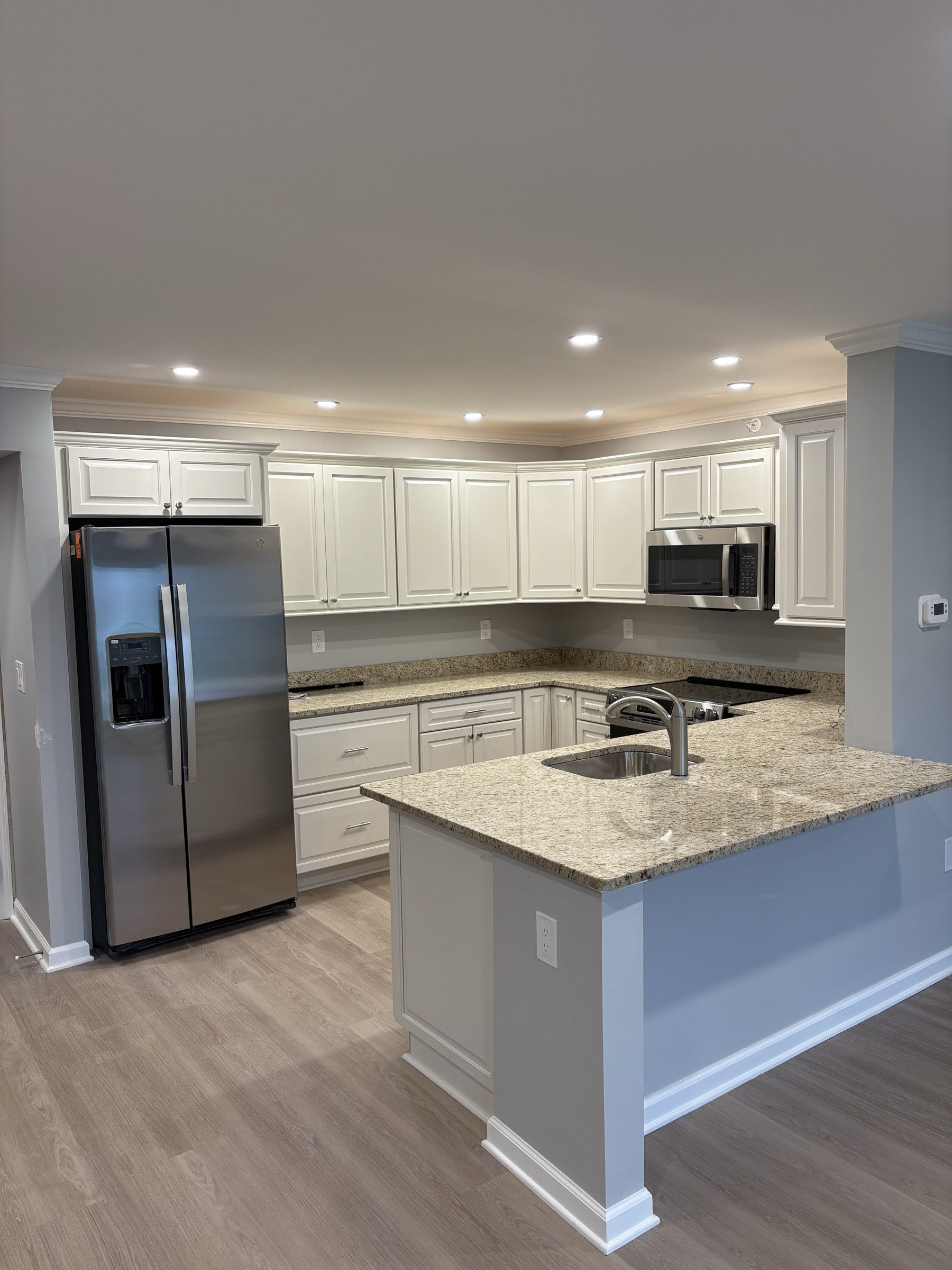 Finished white kitchen with granite countertops and crown molding