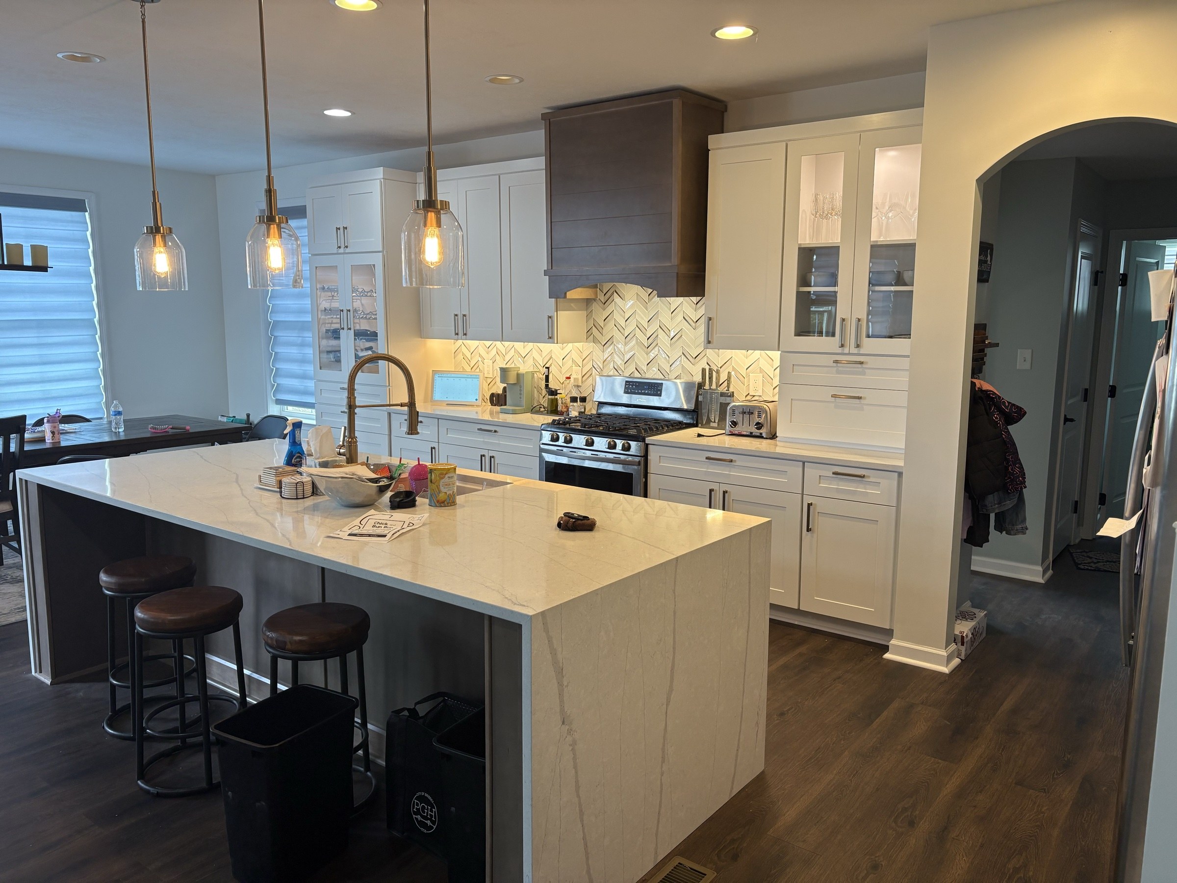 Kitchen with waterfall island, herringbone backsplash and pendants