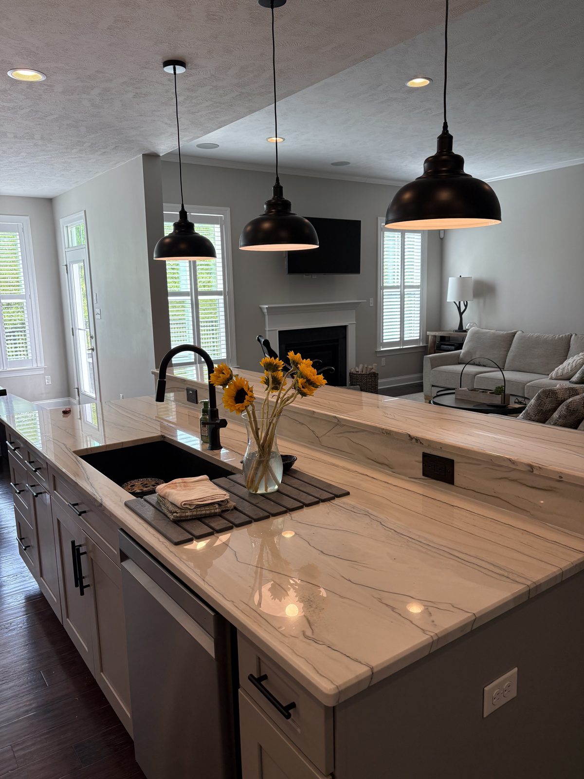 Kitchen island with a dark base, stone countertop and undermount sink