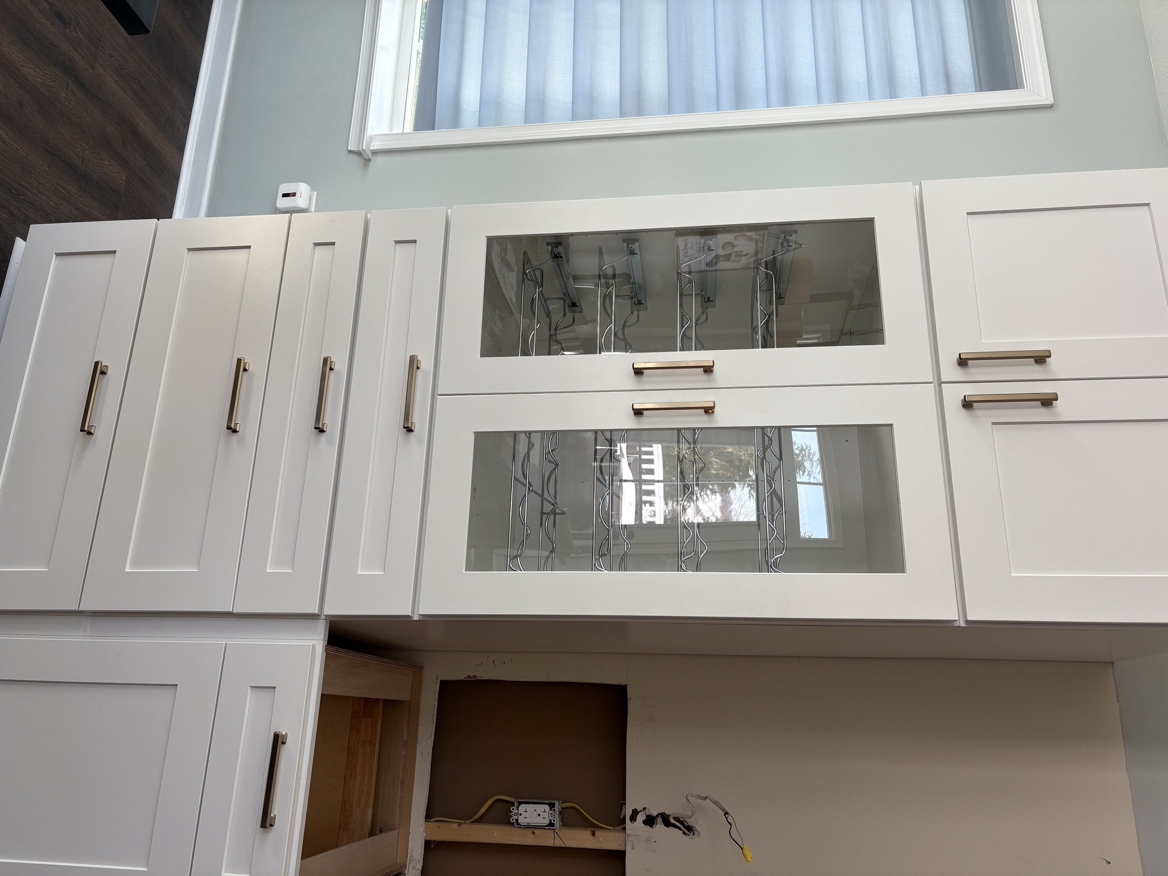 Tall pantry cabinetry with brass pulls and glass wine storage