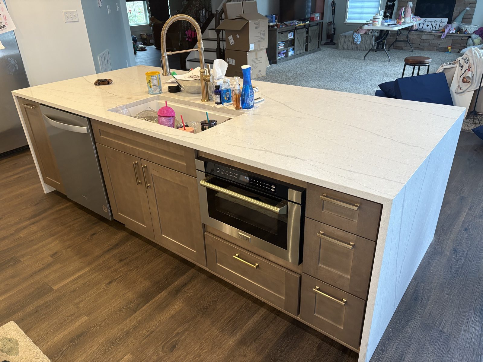 Quartz waterfall island with wood cabinets and a built-in microwave drawer