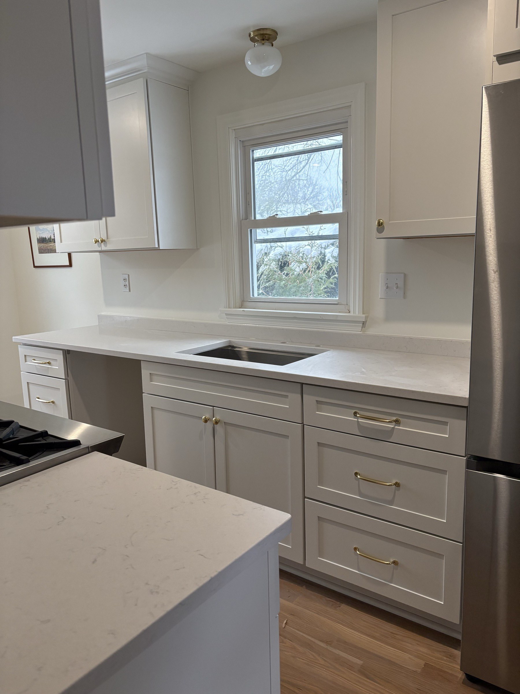 Finished white shaker kitchen with brass hardware and quartz counters by S&P Contracting