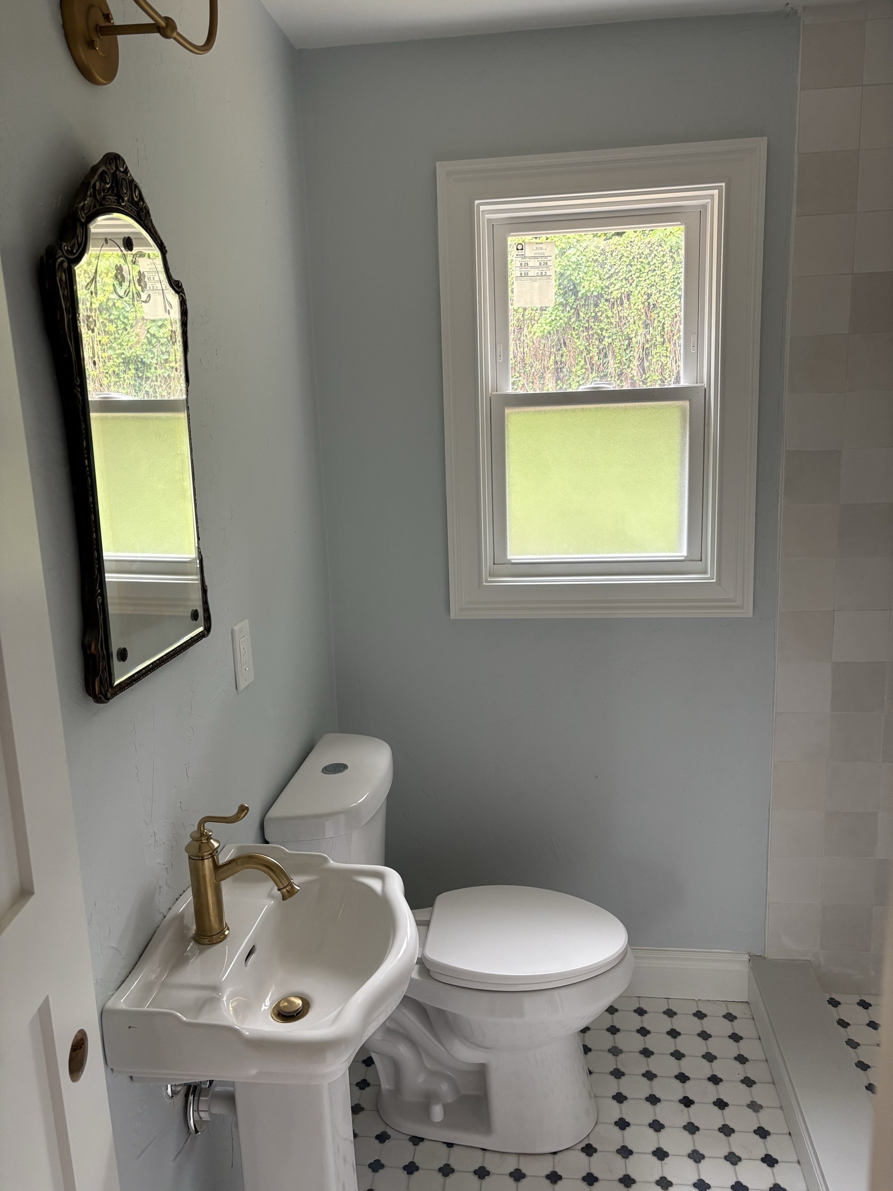 Freshly painted powder room with ornate mirror and pedestal sink