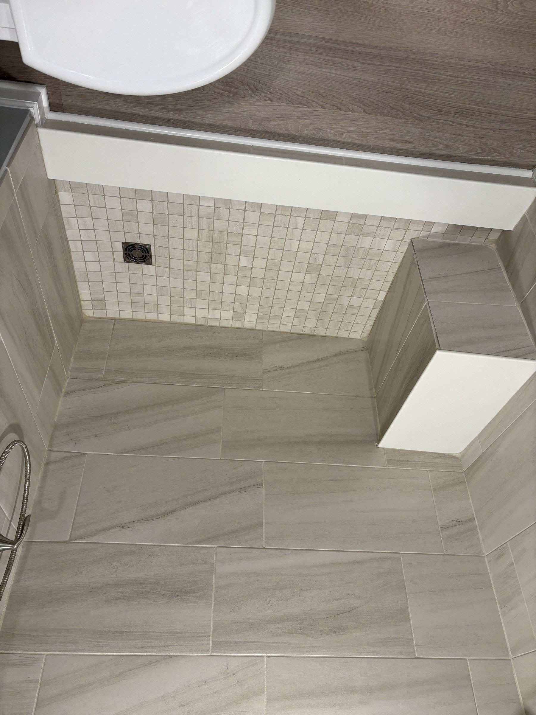 Tile shower floor with mosaic detail and built-in bench